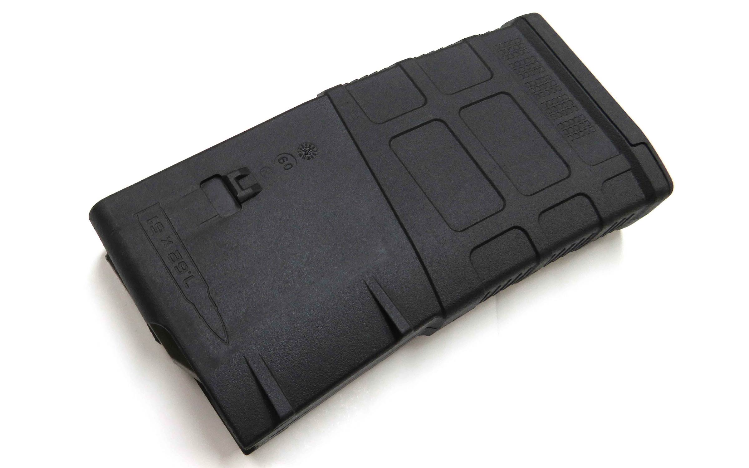 A black polymer rifle magazine is shown lying on a white surface. The magazine features textured grip areas and markings for ammunition capacity.