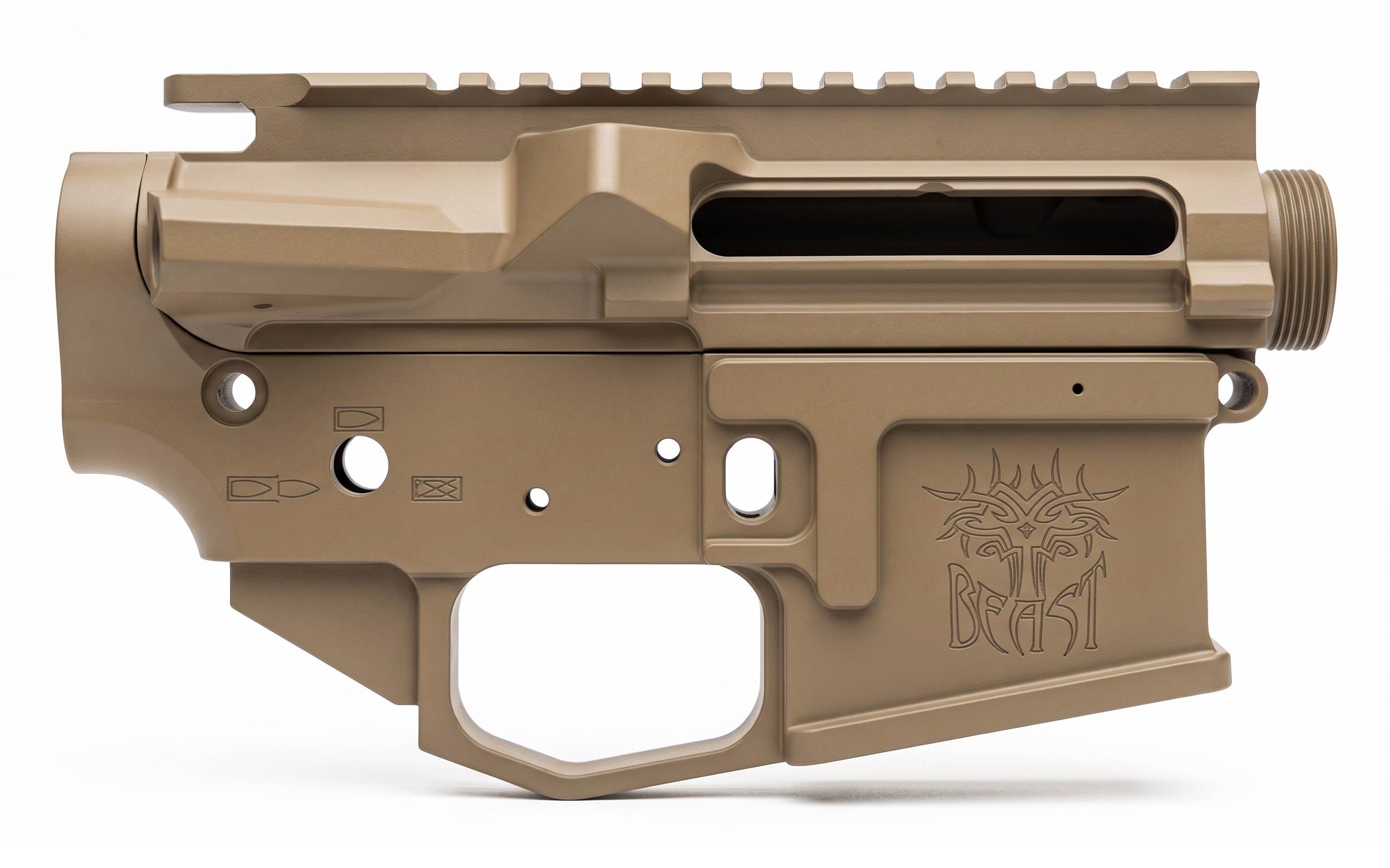 A tan-colored firearm lower and upper receiver combo with Beast and a tribal-style design engraved on the magwell, shown on a white background.
