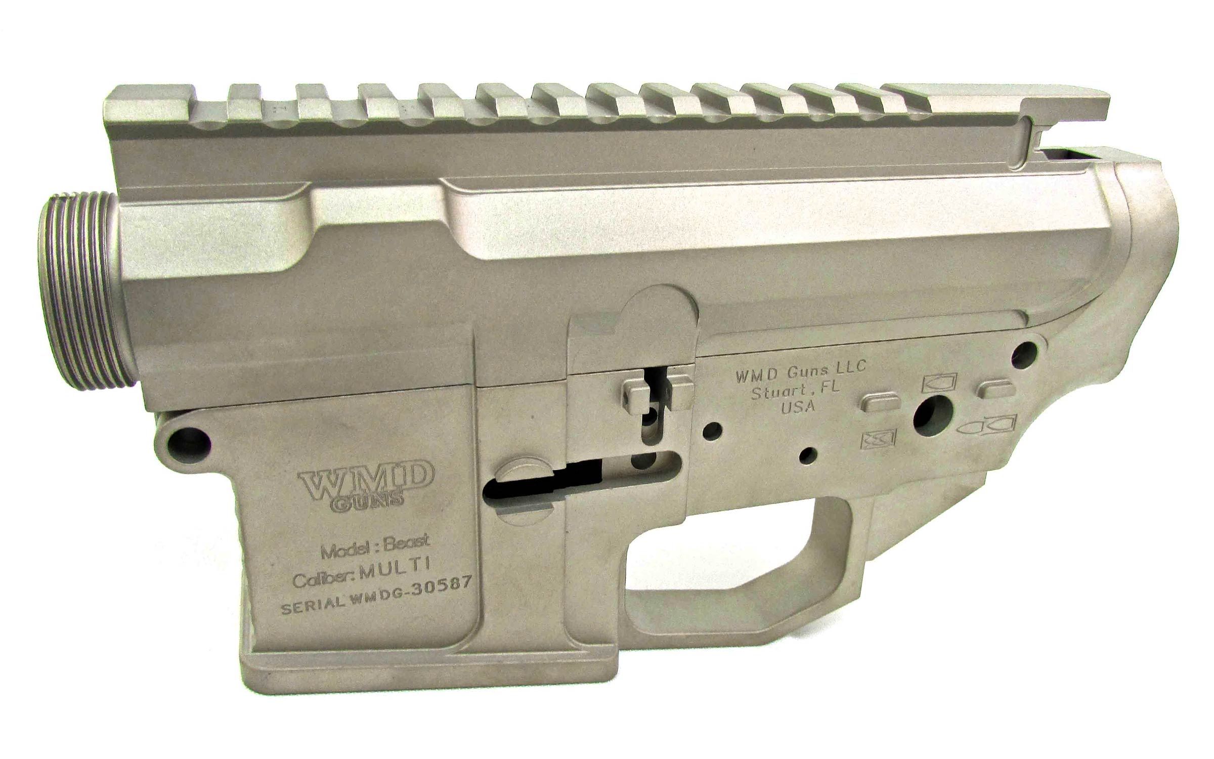 Silver metallic firearm lower receiver with engraved text detailing manufacturer, model, and serial number, viewed from the side against a white background.