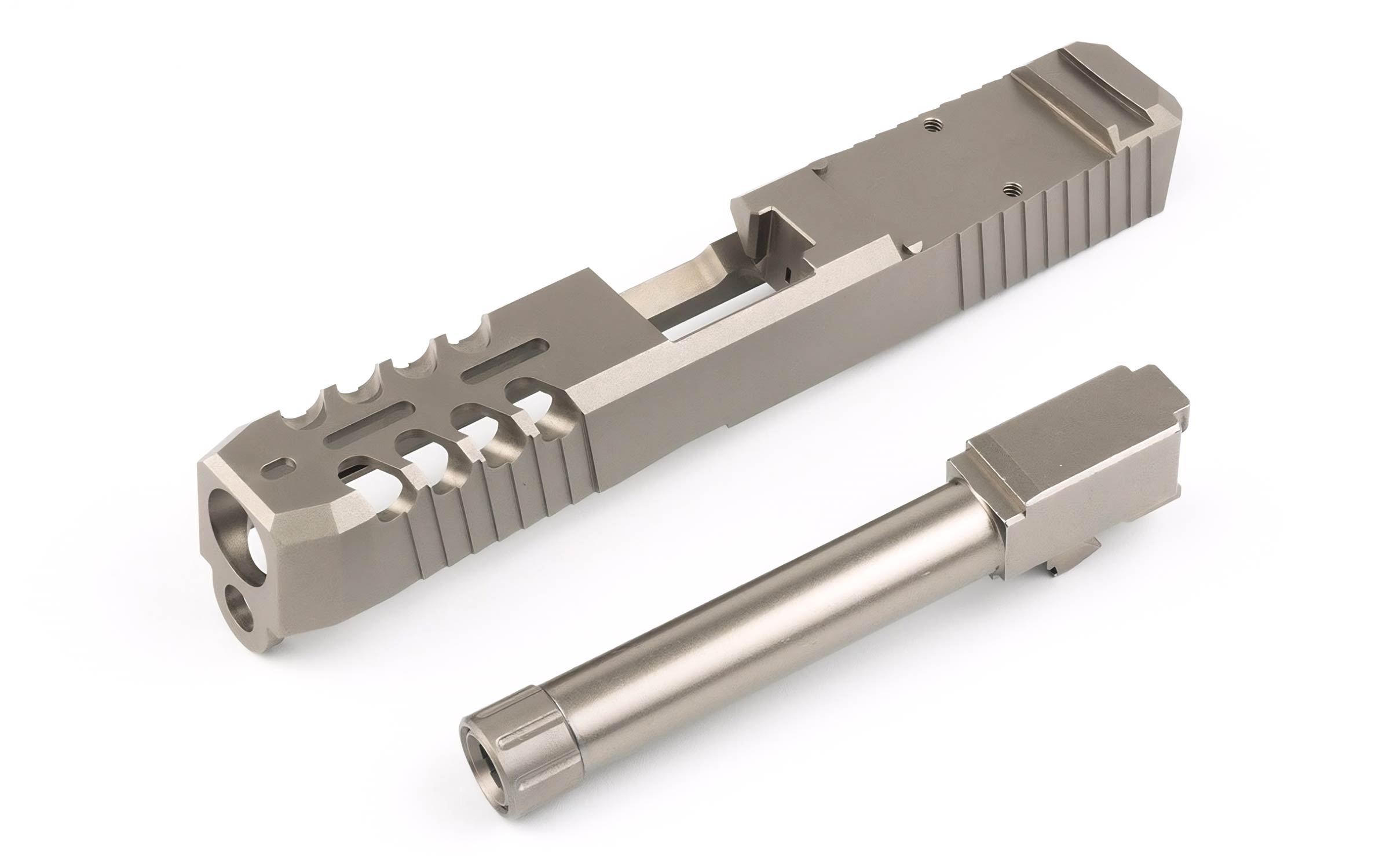 Two metallic firearm components, one resembling a slide with multiple cutouts and the other a barrel, both placed on a white background.