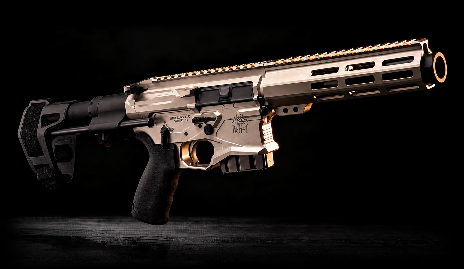 A gold-colored AR-style pistol with a black pistol grip and an arm brace, featuring a Beast logo engraved on the side of the receiver.